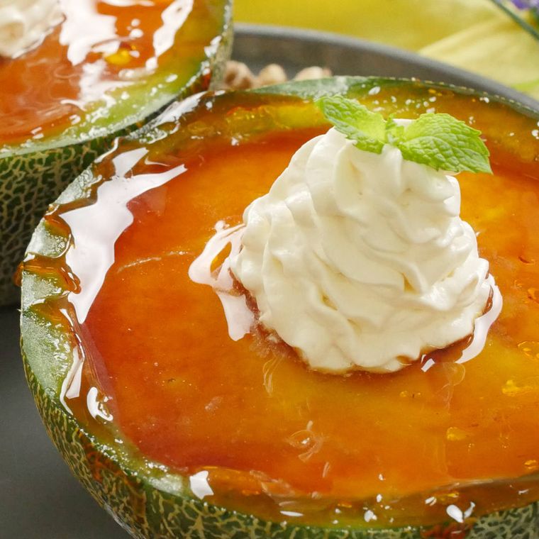 メロンの皮を器にしているメロンのチーズブリュレがグレーの皿にのっている