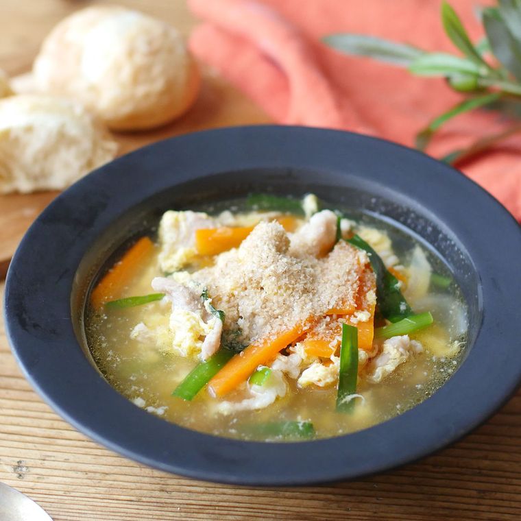 青い皿に盛り付けた豚バラ肉と卵のピリ辛スープ