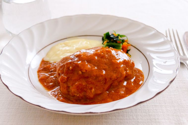 煮込みハンバーグと付け合わせのマッシュポテト、ほうれん草バター炒めを盛り付けた皿