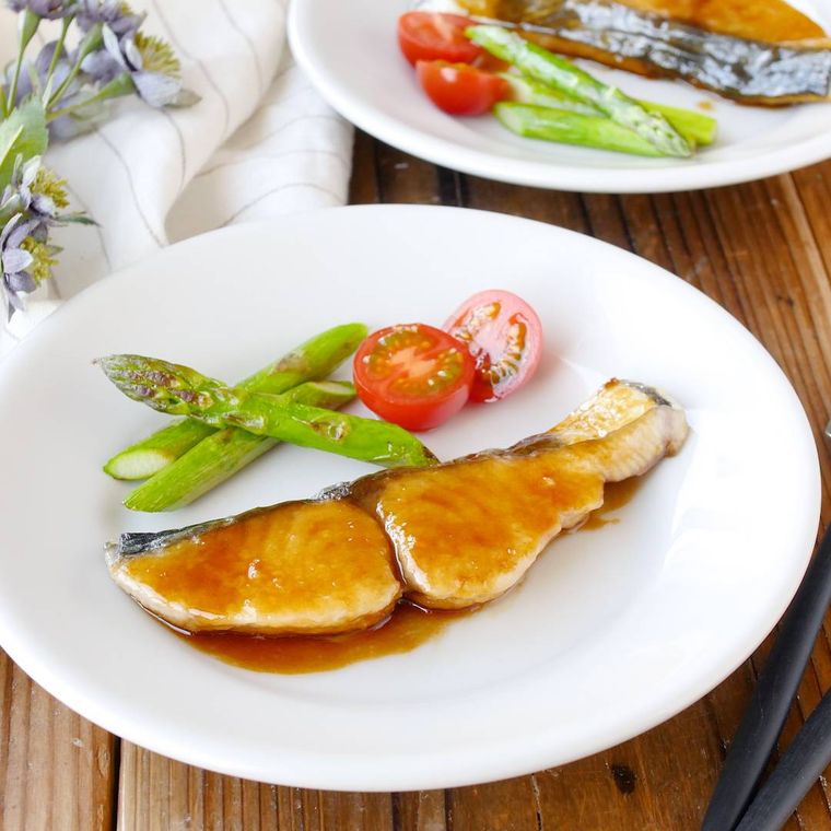 白い皿にのっているさわらのバターしょうゆ焼きと付け合わせの野菜