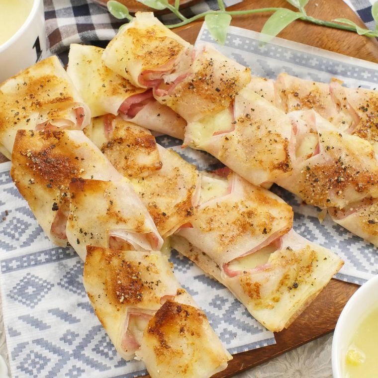 木製のカッティングボードに置かれた春巻の皮でベーコンエピ