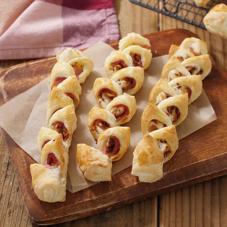 木のボードに紙をしいておかれたパイ生地のベーコンエピ