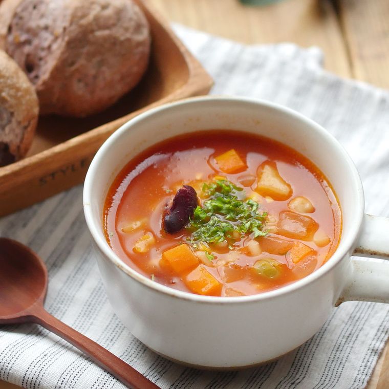 白いスープカップに入った、豆ともち麦のトマトスープ