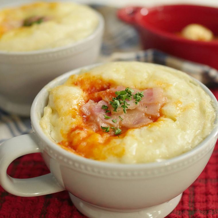 白いマグカップでレンジ加熱されたベーコンとチーズ入りのピザまん
