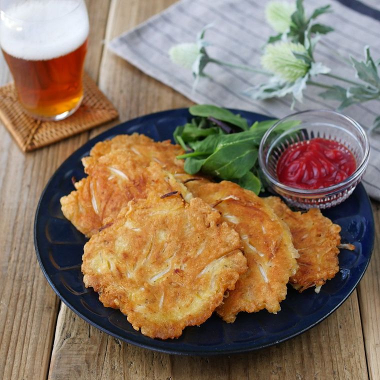 黒いお皿に盛られたもやしとチーズのチヂミとビール