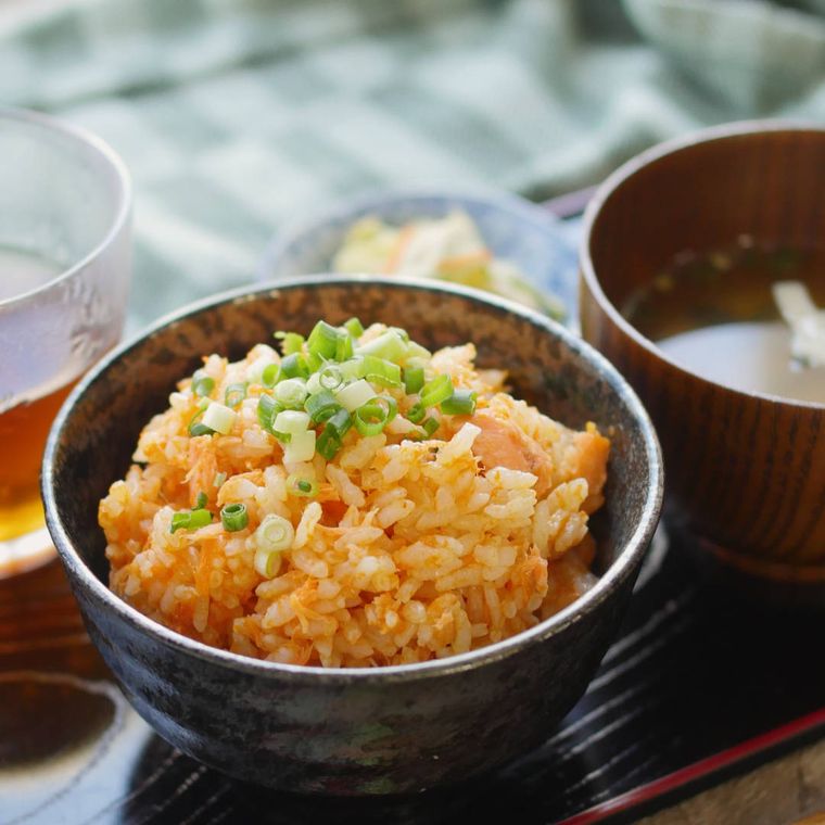 黒っぽい茶碗に盛られた、鮭とにんじんの炊き込みご飯