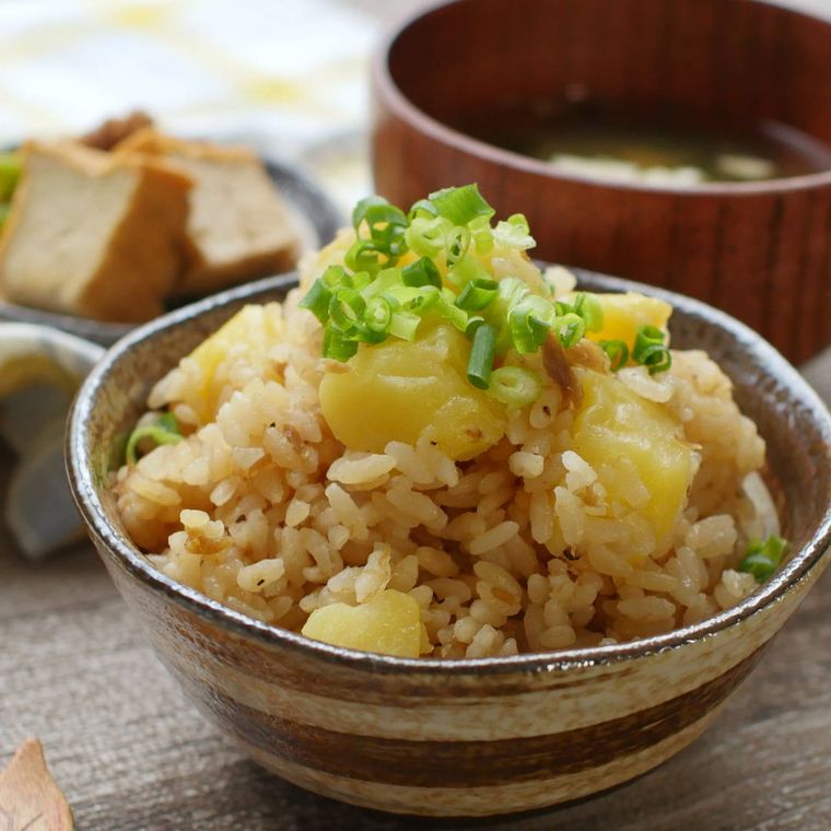茶のラインが入った焼き物茶碗に盛られた、じゃがいもとツナマヨの炊き込みご飯