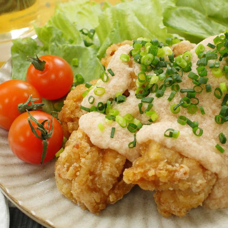 陶器に盛り付けた唐揚げの明太子とろろソースがけと付け合わせのミニトマトやレタス