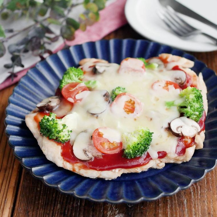 青い皿に盛りつけられた鶏むね肉とブロッコリーの大判ピザ