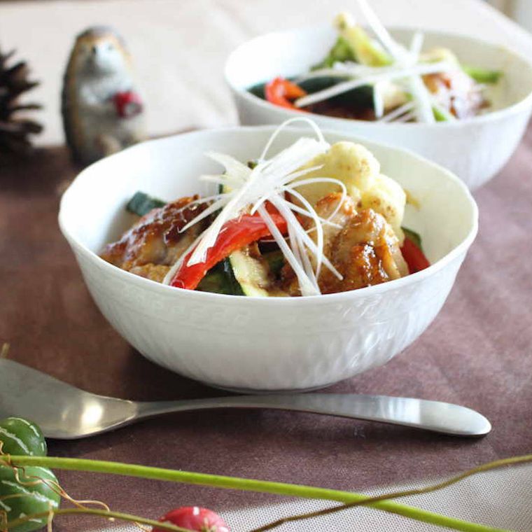 白い器に盛られ、白髪ねぎをトッピングした、鶏もも肉のやきとりと焼き野菜の彩り豊かな丼