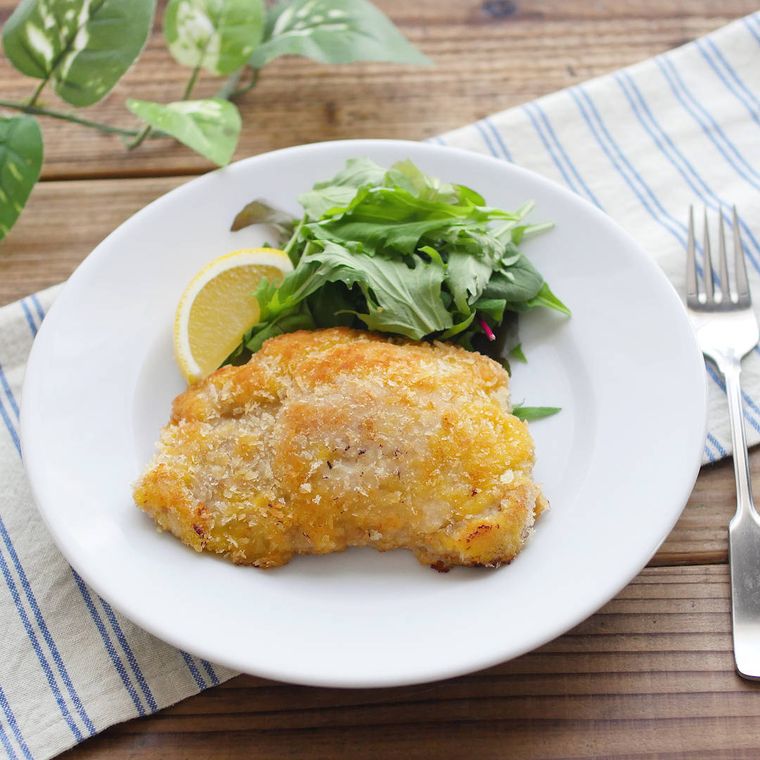 白い皿に盛りつけられた豚ロース肉のミラノ風カツレツとつけ合わせ