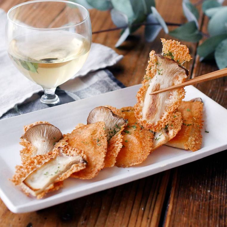 白い長皿に盛りつけられたエリンギのカリカリチーズ焼きと白ワイン