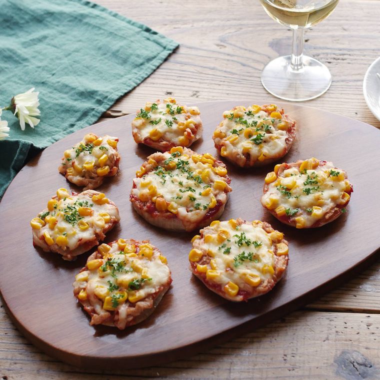 木製プレートに盛りつけられた大小さまざまなツナ缶とコーンのピザ