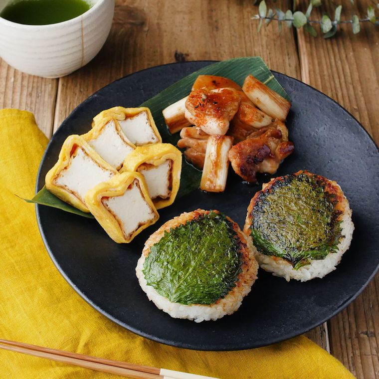 黒いプレートに盛り付けられた大葉味噌おにぎりと厚揚げ卵、焼き鳥