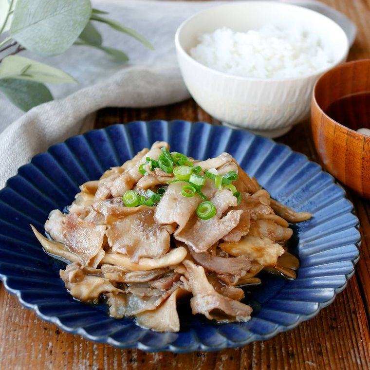青いプレートに盛り付けたまいたけと豚バラ肉の甘辛炒めと、白い茶碗によそったごはん