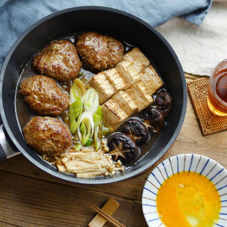 スキレットに入ったすき焼きの煮込みハンバーグと生卵