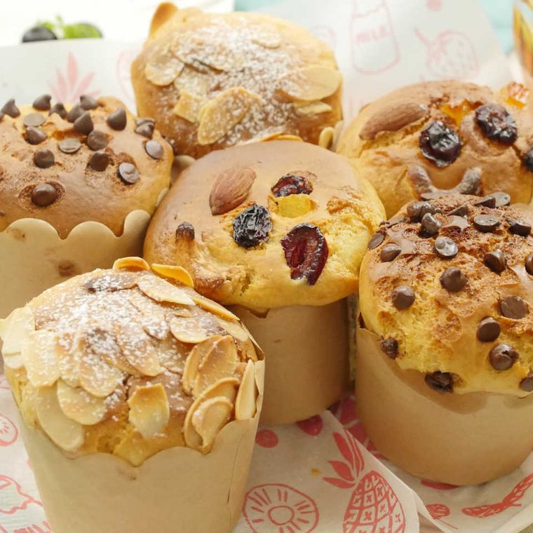 紙の上に置かれた、ナッツやチョコレートをトッピングしたバニラカップケーキ