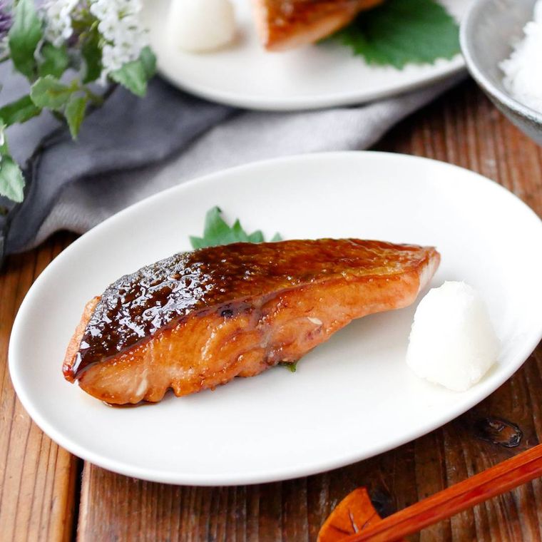 白い皿に盛りつけられている生鮭の照り焼きと大根おろし