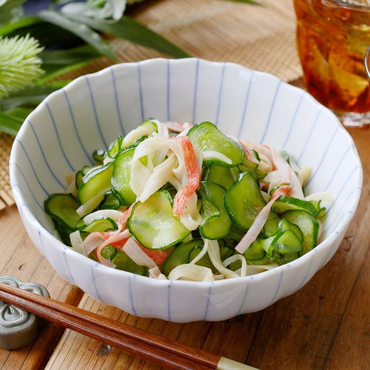 ストライプ模様の小鉢に盛りつけられたカニかまときゅうりの酢の物