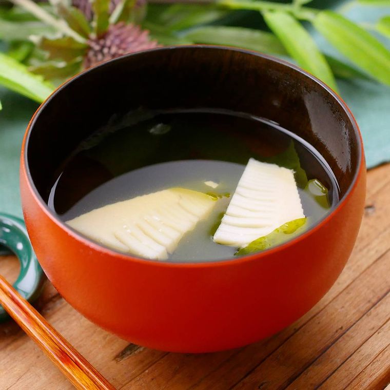 オレンジ色のお椀に盛りつけられたわかめとたけのこのお吸い物