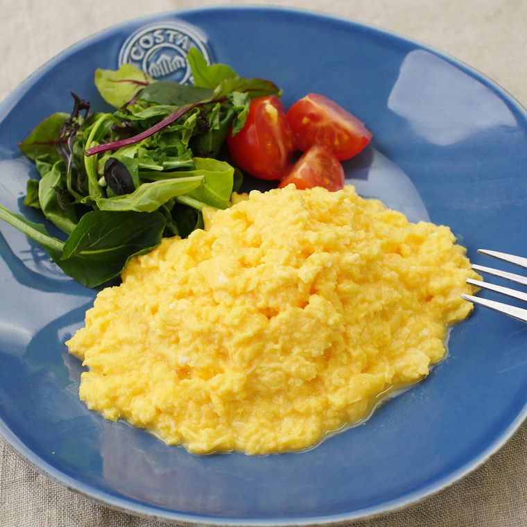 青い皿に付け合わせの野菜と一緒に盛られた、スクランブルエッグ