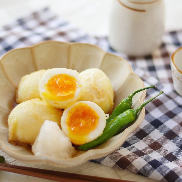 淡いグレー色の器にししとうと一緒に盛られた、半熟卵の揚げ出し