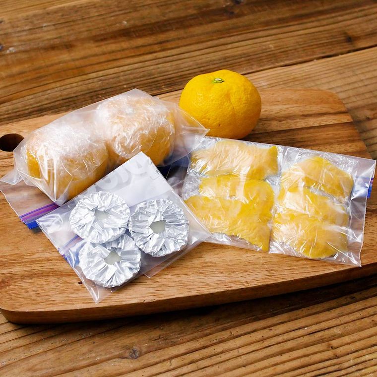 木のボードにおかれた冷凍の柚子、柚子果汁、柚子の皮