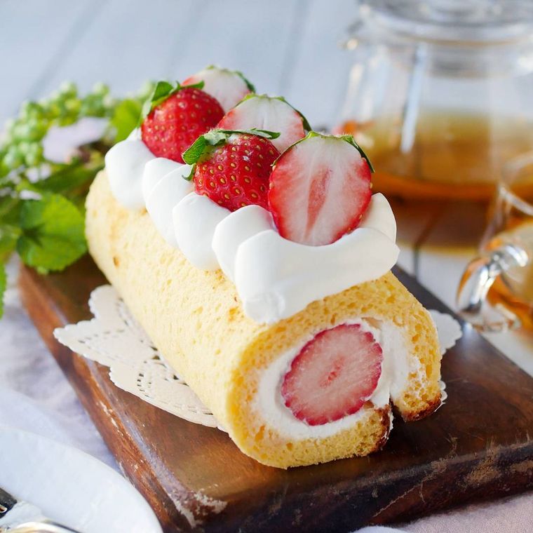 木製のカッティングボードにのったいちごのミニロールケーキ