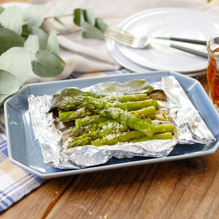 水色の角皿に盛り付けたアスパラガスのホイル焼きと2枚の取り皿