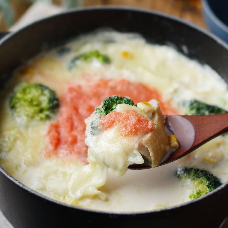 黒い鍋に入っている鶏もも肉とブロッコリー、明太子のチーズ鍋