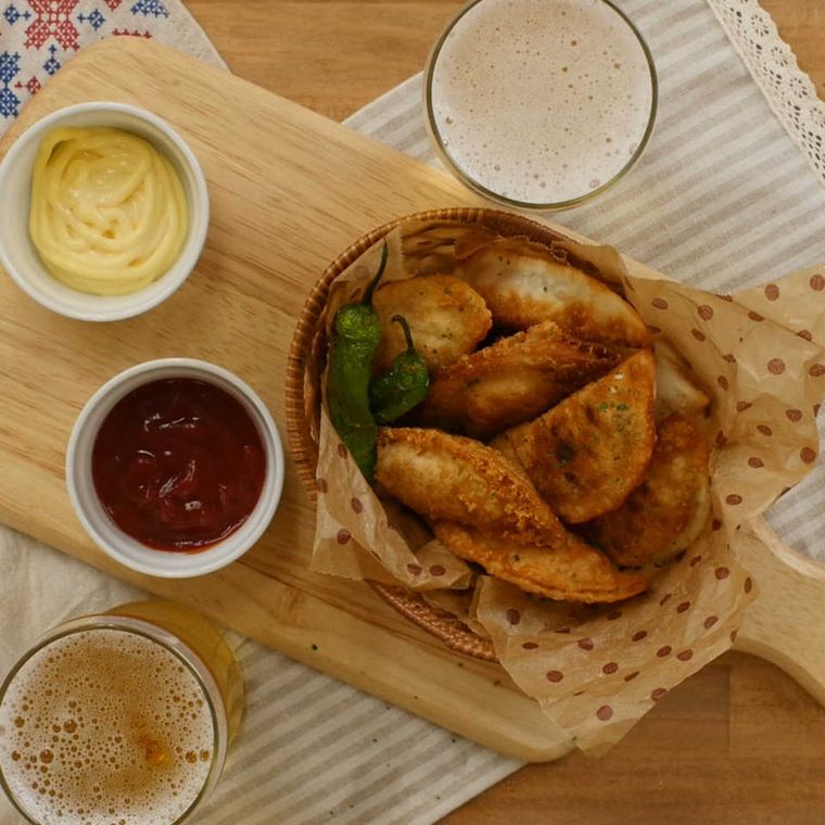 木のボードに盛られたアボカドと生ハムチーズの揚げ餃子