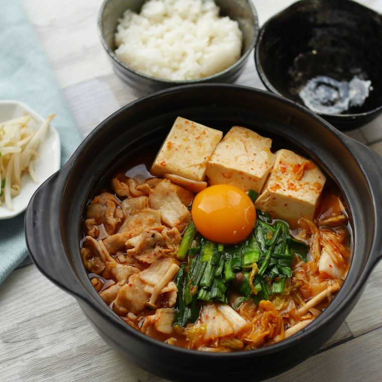 黒い両手鍋に盛りつけられた豚肉としめじ入りのスンドゥブチゲ