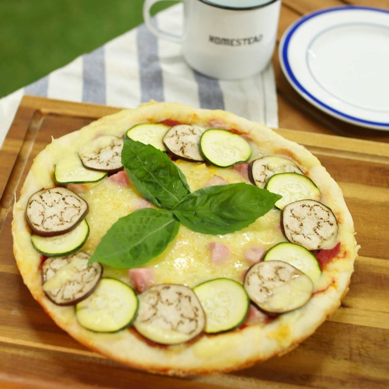 カッティングボードの上の夏野菜のワンパンピザ