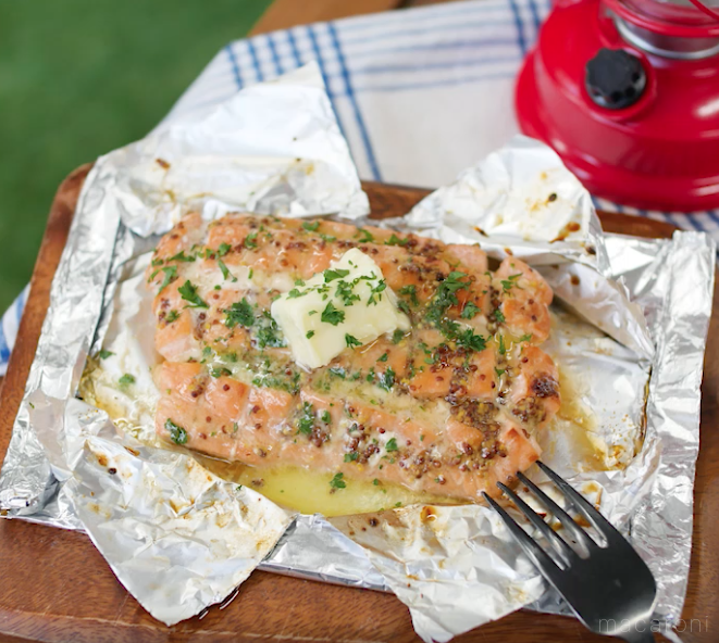 ホイル焼きにしたサーモンがのせられたカッティングボードとフォーク