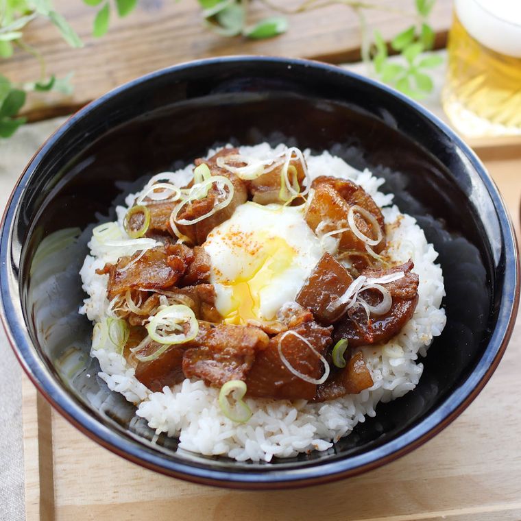 黒い丼に盛り付けられ、ビールが添えられた豚バラ肉のどて煮風丼
