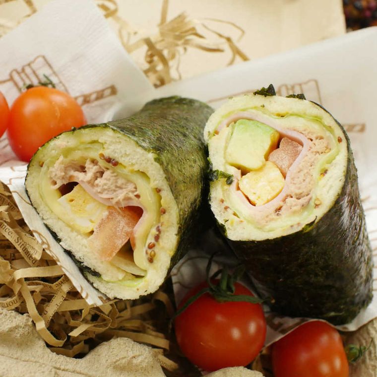 敷き紙に盛りつけられたハムとアボカド入り恵方巻きサンドイッチ