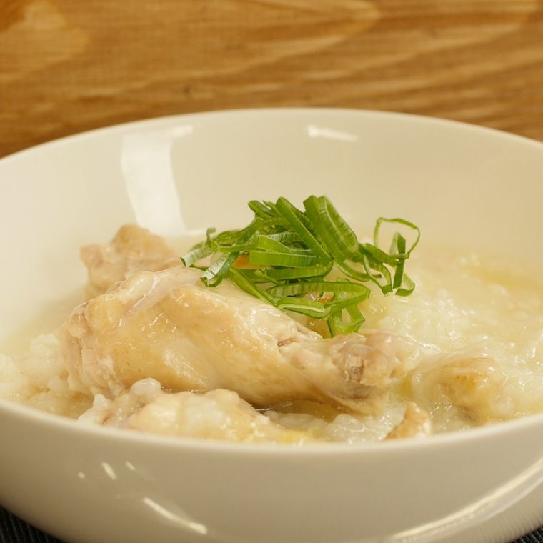 白い丼鉢に盛りつけられた鶏手羽元と長ねぎ入りサムゲタン風雑炊
