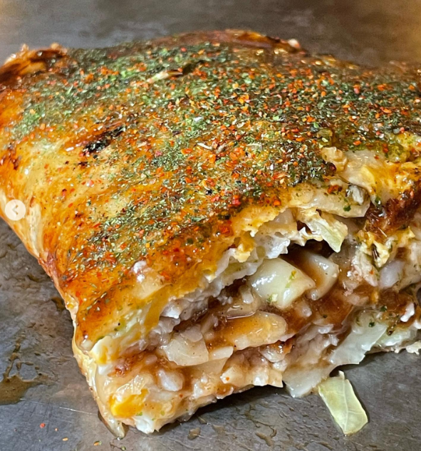 鉄板の上で半分に切ったはやしのお好み焼きのとくしま豆玉