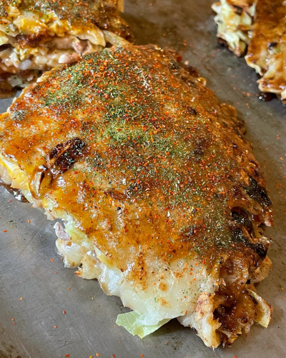 鉄板の上で焼かれているはやしのお好み焼きのとくしま豆玉