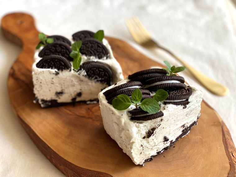 木製トレーにのせてミントを飾り付けた濃厚オレオチーズケーキと金のフォーク