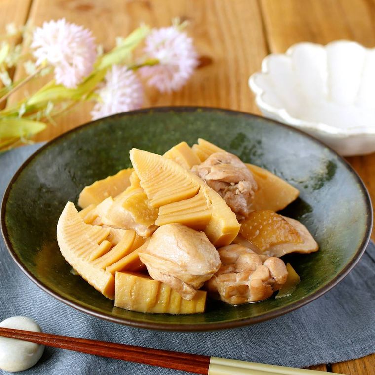 深緑色の器に盛り付けたたけのこと鶏肉の煮物