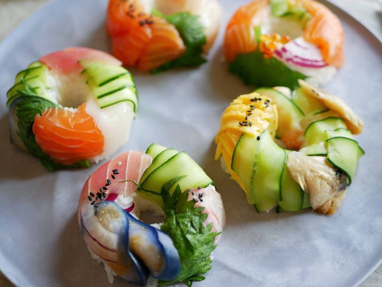 彩りのよい寿司ドーナツが5個皿の上に並んでいる様子