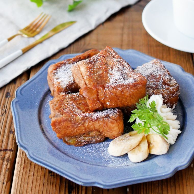 青い皿にバナナフレンチトーストとカットバナナ、ホイップクリームが盛られている様子