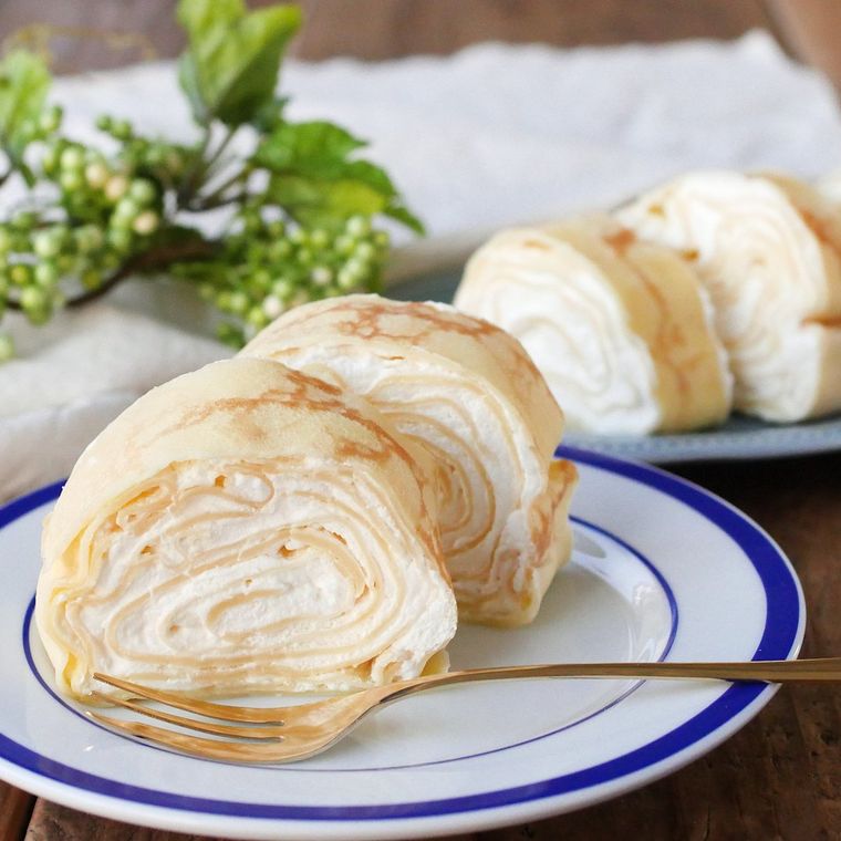 青い模様入りの白い皿に盛られたロールクレープと、添えられたフォーク