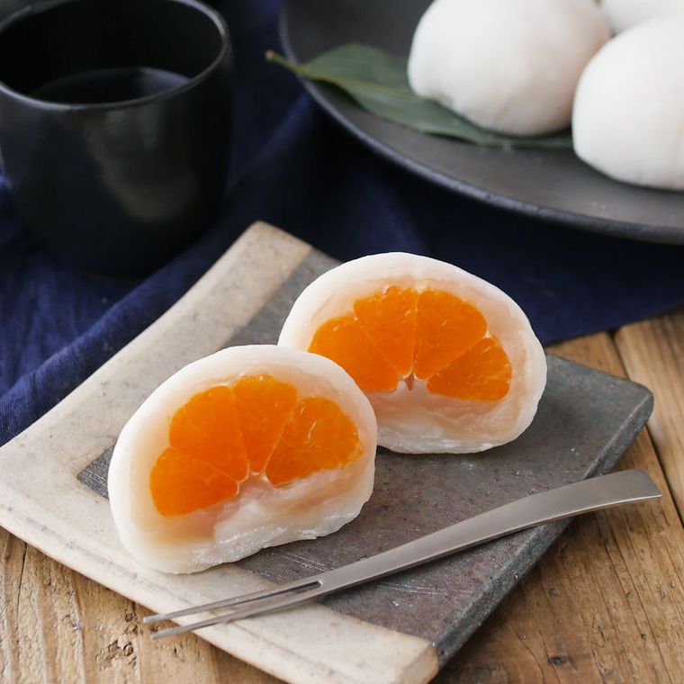 四角い皿に半分にカットして盛られたみかん大福