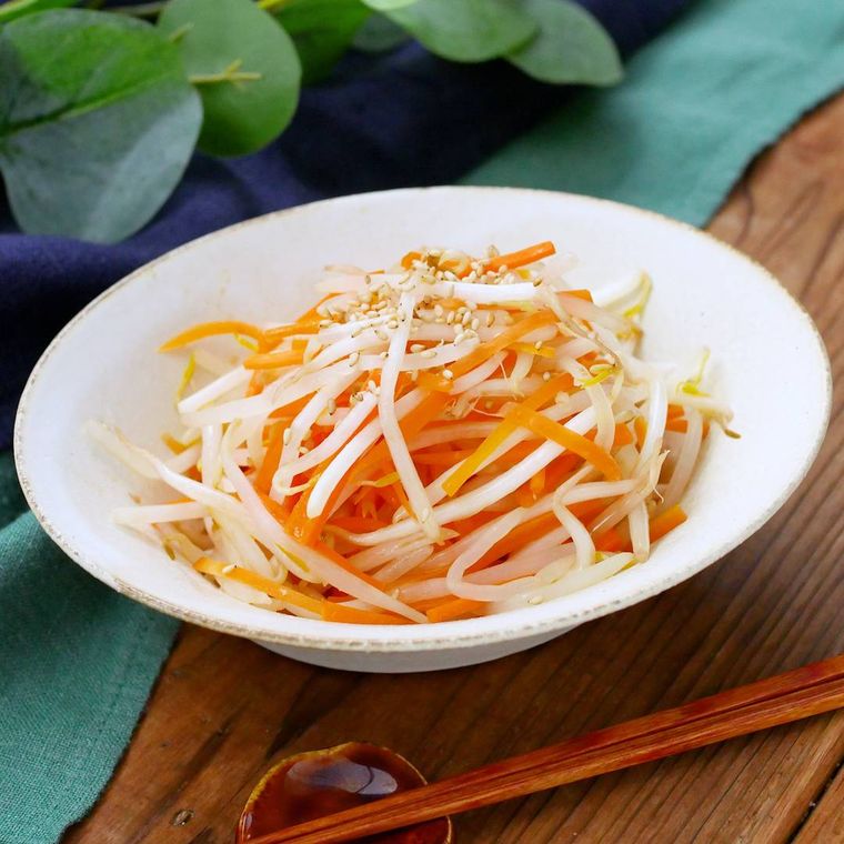 ベージュの皿に盛り付けられているもやしとにんじんのナムル