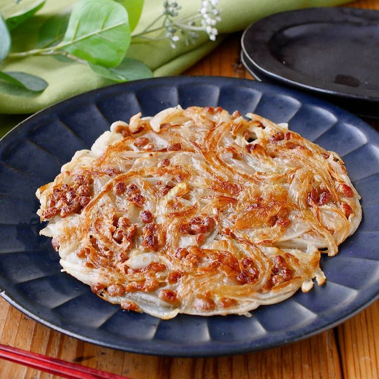 青い皿にのっている納豆と玉ねぎのもちもち焼き