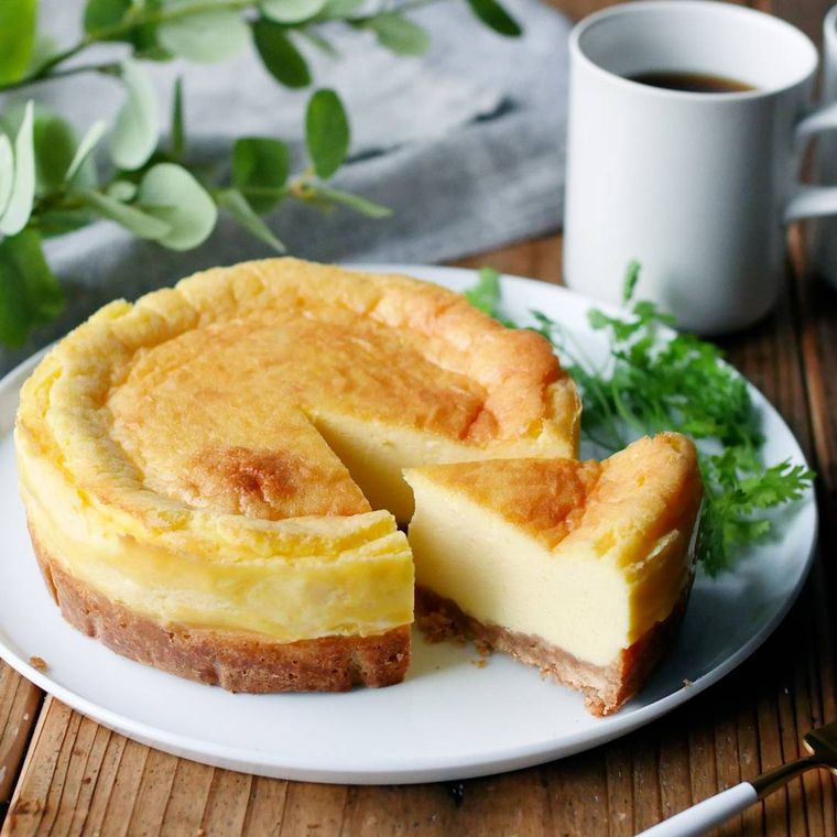 白い皿にニューヨークチーズケーキのホールがのっている