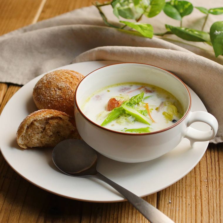 白い皿に盛られた、白菜のポタージュ、スプーン、添えられたパン