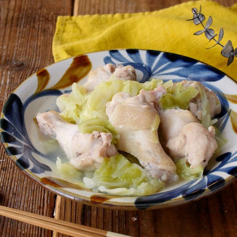 青色や茶色の模様が入った皿に盛られた鶏手羽元とキャベツの塩煮込み